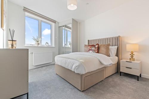 a white bedroom with a bed and two windows at Thameside Suite | Free Parking | 2 BR | Heathrow in Staines
