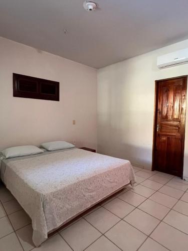 a bedroom with a bed and a wooden door at Casa com piscina em Canoa Quebrada in Canoa Quebrada