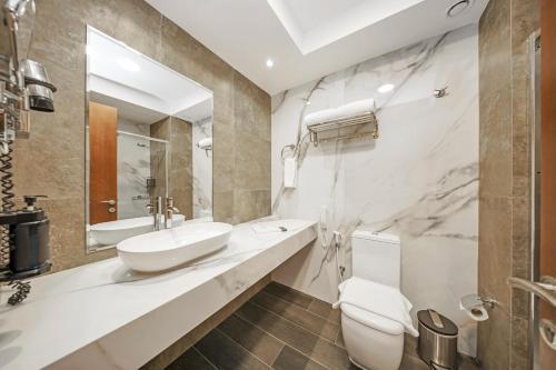 a white bathroom with a sink and a toilet at Acacia Hotel Ras Al Khaimah by AMR in Ras al Khaimah