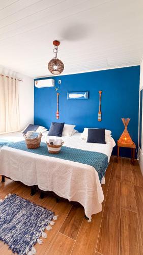 a bedroom with two beds and a blue wall at Recanto Manoah MAR in Caraíva
