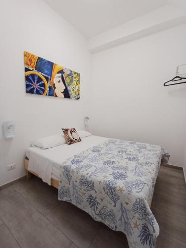 a bed in a white room with a picture on the wall at Studio 23 in Partinico