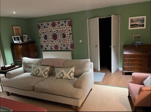a living room with a white couch and green walls at Riverside Cottage Sleeps 8 with Parking in Marlborough
