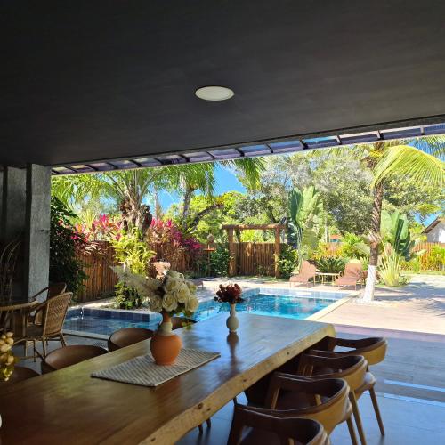 a dining room with a table and a swimming pool at Pousada Sky Dream Beach Mutá Frente Mar By LVF in Porto Seguro
