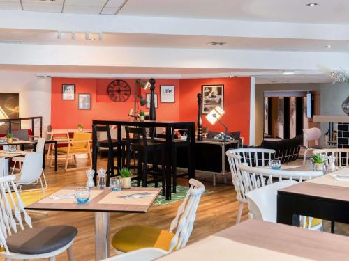 a restaurant with orange walls and tables and chairs at Novotel Paris Rueil Malmaison in Rueil-Malmaison