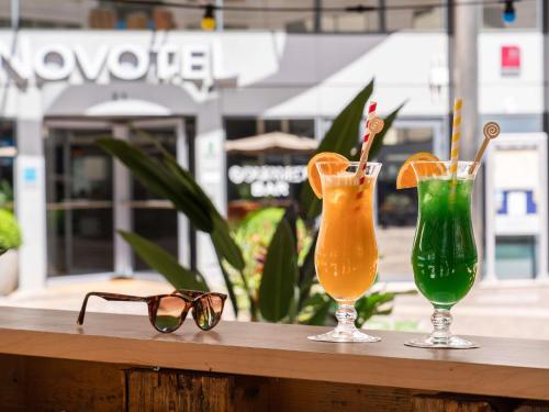 two glasses and two cocktails on a wooden table at Novotel Paris Rueil Malmaison in Rueil-Malmaison