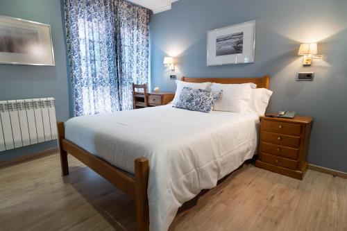 a bedroom with a large bed with a nightstand and a window at Hotel Arco Navia in Navia