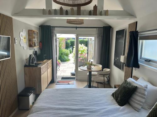 a bedroom with a bed and a table and a patio at Style Gardenhouse Zwanenburg near AMSTERDAM, HAARLEM, ZANDVOORT in Zwanenburg