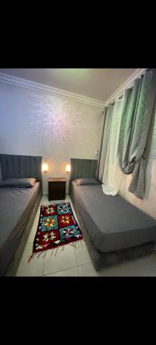 a bedroom with two beds and a rug on the floor at Benjelloun in Marrakesh