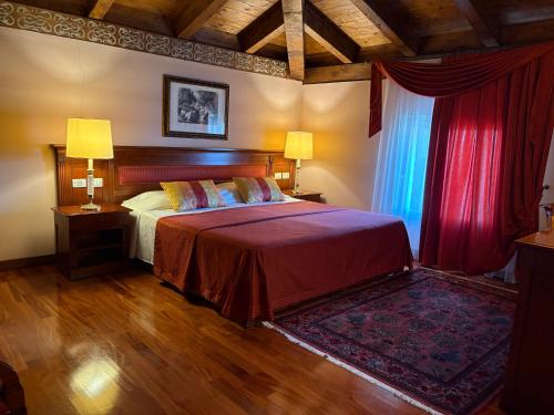 a bedroom with a large bed with red curtains at Le Muse Hotel in San Bonifacio