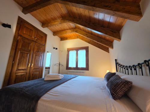 a bedroom with a large bed with wooden ceilings at El balcón de Cotefablo Chalet de Montaña con Jardín y Vistas - Arafita Apartamentos in Gavín