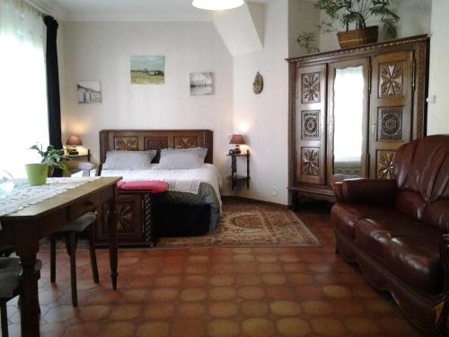 1 dormitorio con cama, mesa y sofá en Chambres d’hotes vue sur la Campagne, en Marquise