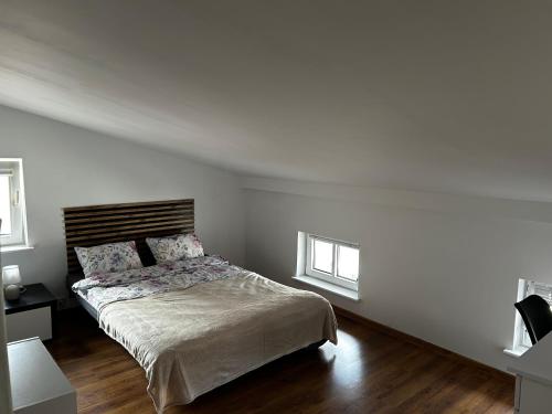 a white bedroom with a bed and two windows at Nadmorska Przystań in Ustka