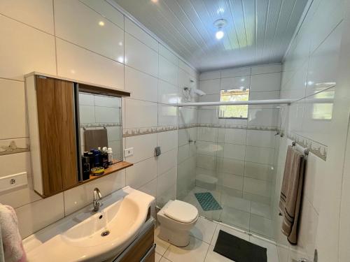 a white bathroom with a sink and a toilet at Chácara com piscina, lazer e muita natureza in Morretes