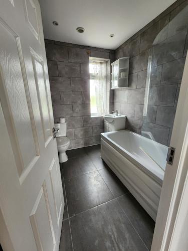 a bathroom with a tub and a sink and a toilet at The Willow in Aveley