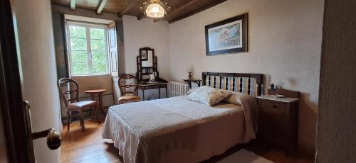 a bedroom with a bed and a desk and a window at Casa Vixide in Lalín