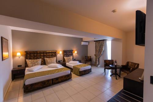ein Hotelzimmer mit zwei Betten und einem Fernseher in der Unterkunft Amalias Hotel in Kourouta