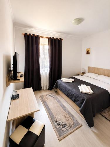 a bedroom with a bed and a table and a window at CAZARE TURISM PRISLOP in Haţeg