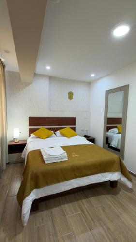 a bedroom with a large bed with yellow pillows at Hotel Residencial Paris in Arequipa