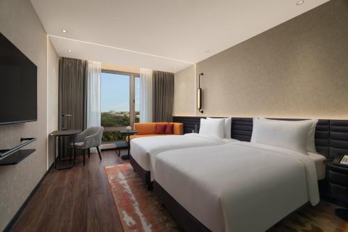 a hotel room with a large bed and a desk at Novotel Bhubaneswar Janpath in Bhubaneshwar