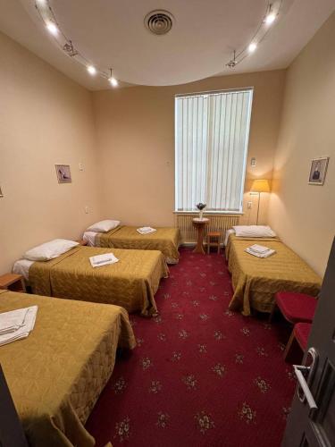 a room with three beds and a red carpet at Fortuna hostel in Odesa