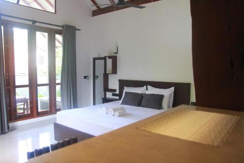 a bedroom with a large white bed and a window at Rock Harmony Villa in Dodanduwa