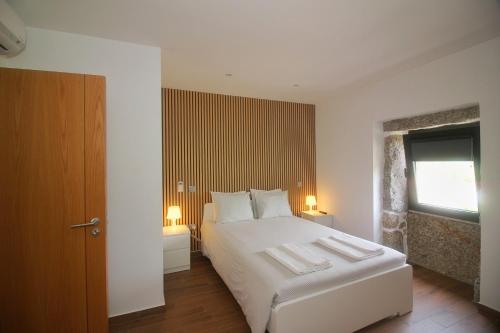 a bedroom with a white bed and a window at Casa do Mestre by Gerês Casas in Geres