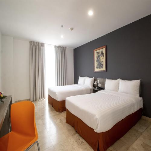 a hotel room with two beds and a chair at Hotel SI Chapala in Chapala
