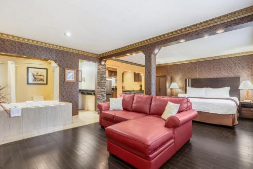a hotel room with a bed and a red couch at Days Inn by Wyndham Sylvan Lake in Sylvan Lake