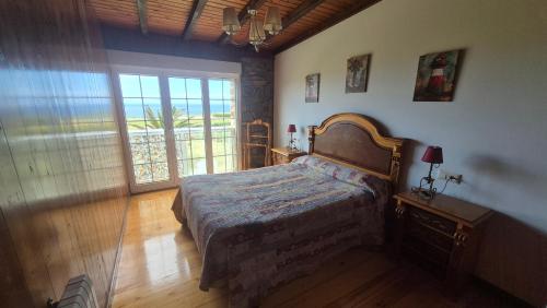 a bedroom with a bed and a large window at La Morada del CABO PEÑAS Folu - Gozón - Luanco in Ferrero