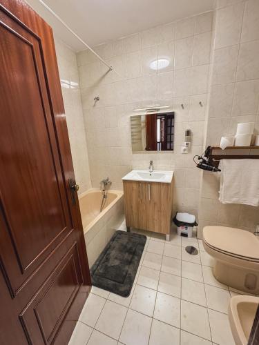 a bathroom with a toilet and a sink and a tub at Titi's House in Gulpilhares