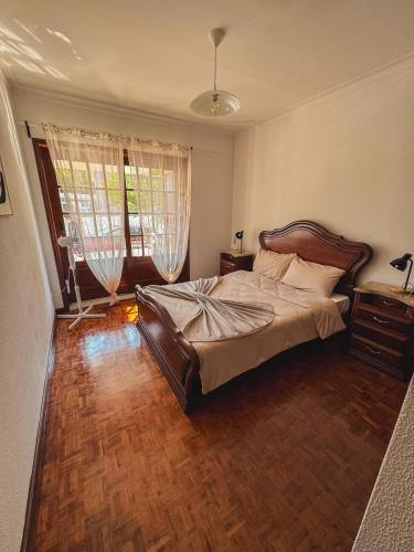 a bedroom with a large bed and two windows at Titi's House in Gulpilhares