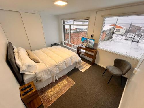 a bedroom with a bed and a window and a chair at The White House Hostel in Puerto Natales