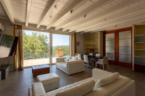 a living room with white furniture and a large window at Sunset Serenity Villa in Padenghe sul Garda