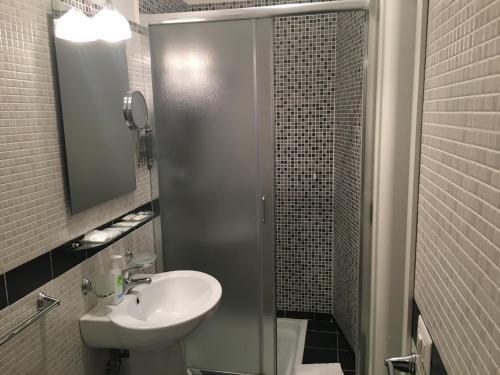 uma casa de banho com um lavatório e um chuveiro com um espelho. em SunMoon em Reggio di Calabria