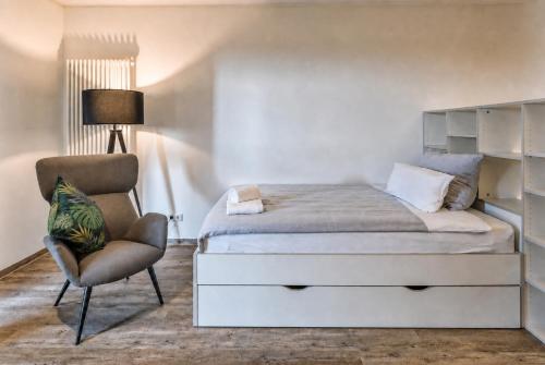 a bedroom with a bed and a chair at MIILOX Apartments Dresden in Dresden