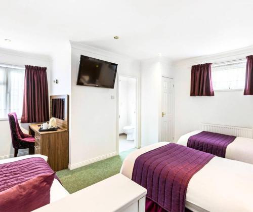 a hotel room with two beds and a flat screen tv at Sandy Lodge Hotel Newquay in Newquay