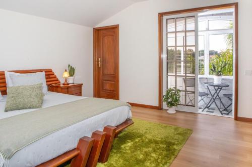 a bedroom with a large bed and a balcony at Casa do Lago guest house in Espinho