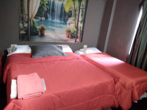 two beds in a room with red sheets at HOSPEDAJE DODERA in Gualeguaychú