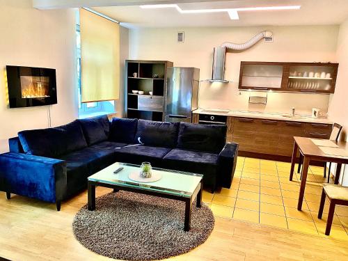 a living room with a blue couch and a kitchen at Klaipeda City Center Aparment in Klaipėda
