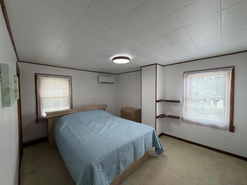 a small bedroom with a bed and two windows at Floral Canal-Facing Hideaway in Chesapeake City
