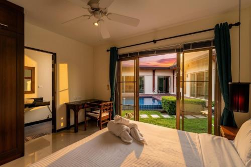 a bedroom with a bed and a view of a yard at Emerald Pool Villa Lush Villa On A Sunny Island in Nai Harn Beach