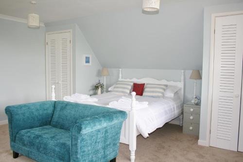 a bedroom with a bed and a blue chair at Hare Lodge B&B in Tisbury