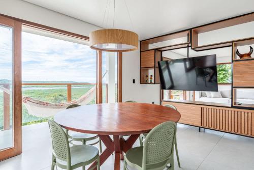 a dining room with a table and chairs and a tv at River & Ocean View House with Pool in Igarassu