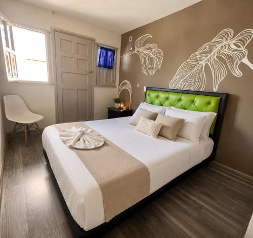 a bedroom with a large bed with a green headboard at Hotel Las Flores in Santa Rosa de Cabal