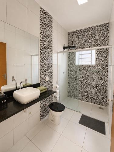 a bathroom with a toilet and a sink and a shower at Casa Completa próxima ao Centro in Passos