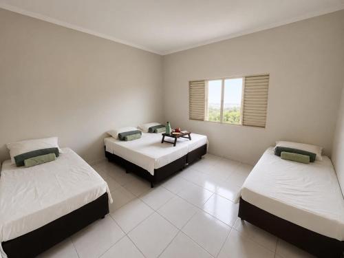 a bedroom with two beds and a table in it at Casa Completa próxima ao Centro in Passos