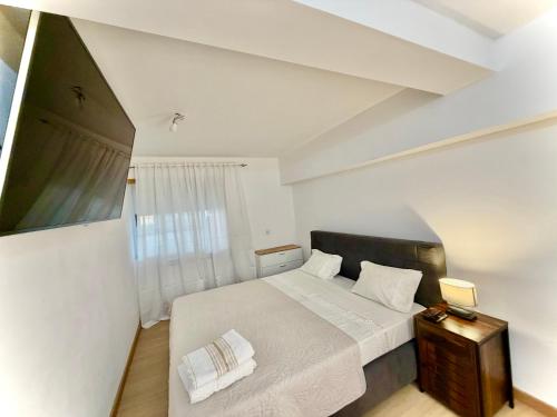 a white bedroom with a bed and a window at Estúdio com cozinha e casa de banho! in Bragança