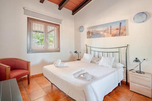 a bedroom with a white bed and a chair at Petit Son Bauló in Can Picafort