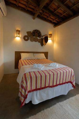 a bedroom with a bed with a red and white striped blanket at Vila Maré Alta Caraiva in Caraíva