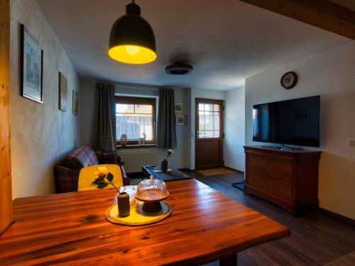 a living room with a wooden table and a television at Ferienwohnung Cozy Cottage in Morbach